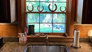 A kitchen with a large window, a sink, and wooden cabinets.