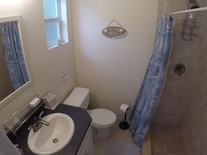 Un baño con lavamanos, inodoro y cortina de ducha blancos.