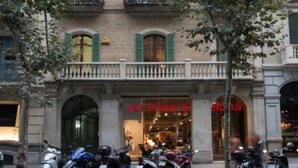 Un edificio con varios balcones, una tienda con letrero y varias motocicletas estacionadas.