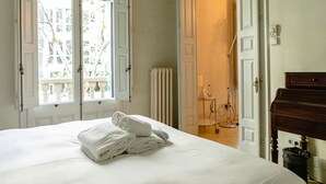 Una habitación de hotel con cama, un radiador, un piano y vistas por una ventana.