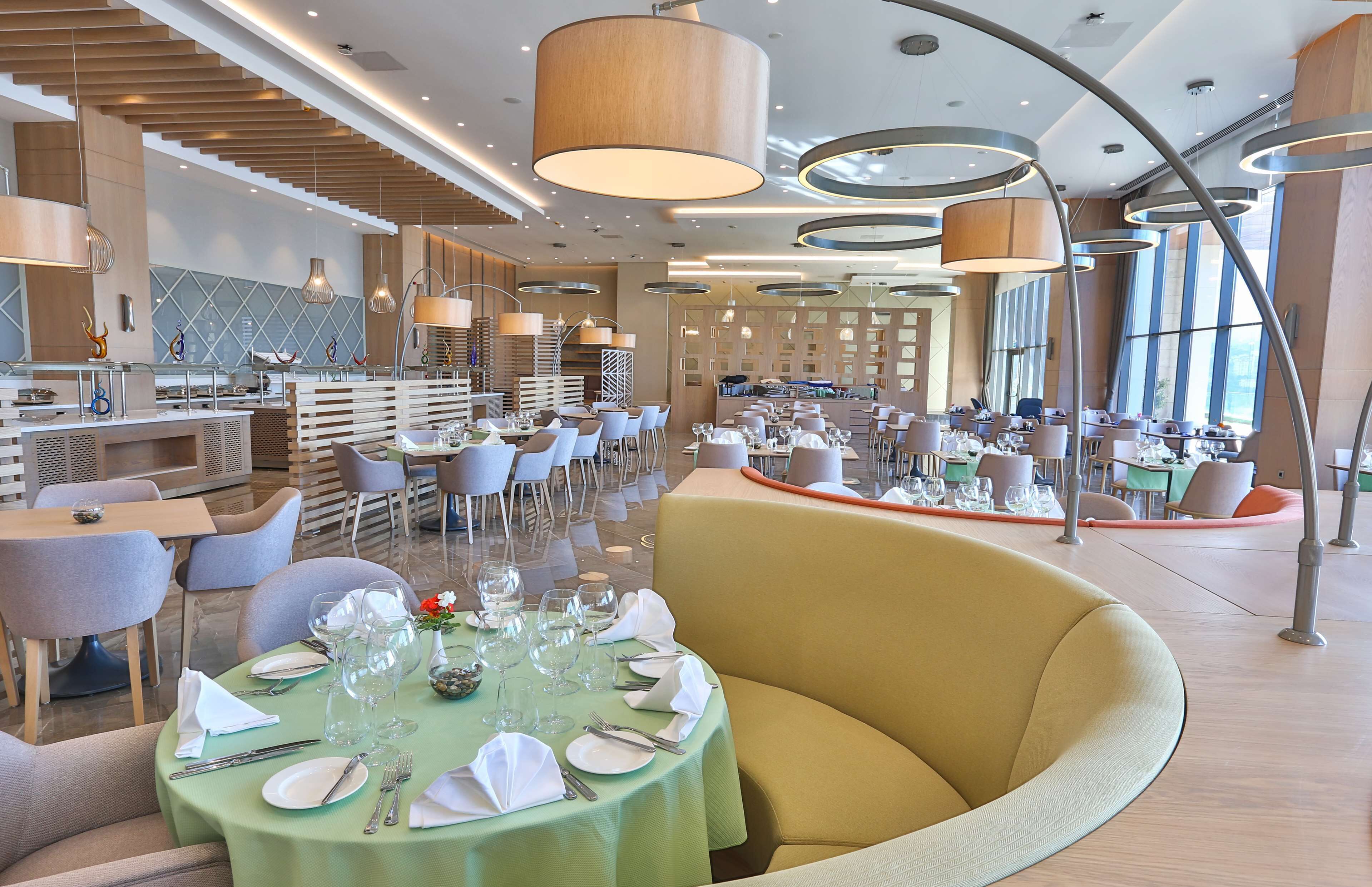 Ein modernes Restaurant mit runden Tischen, bequemen Sitzgelegenheiten und ansprechendem, zeitgenössischem Interieur.