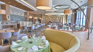 Ein modernes Restaurant mit runden Tischen, bequemen Sitzgelegenheiten und ansprechendem, zeitgenössischem Interieur.