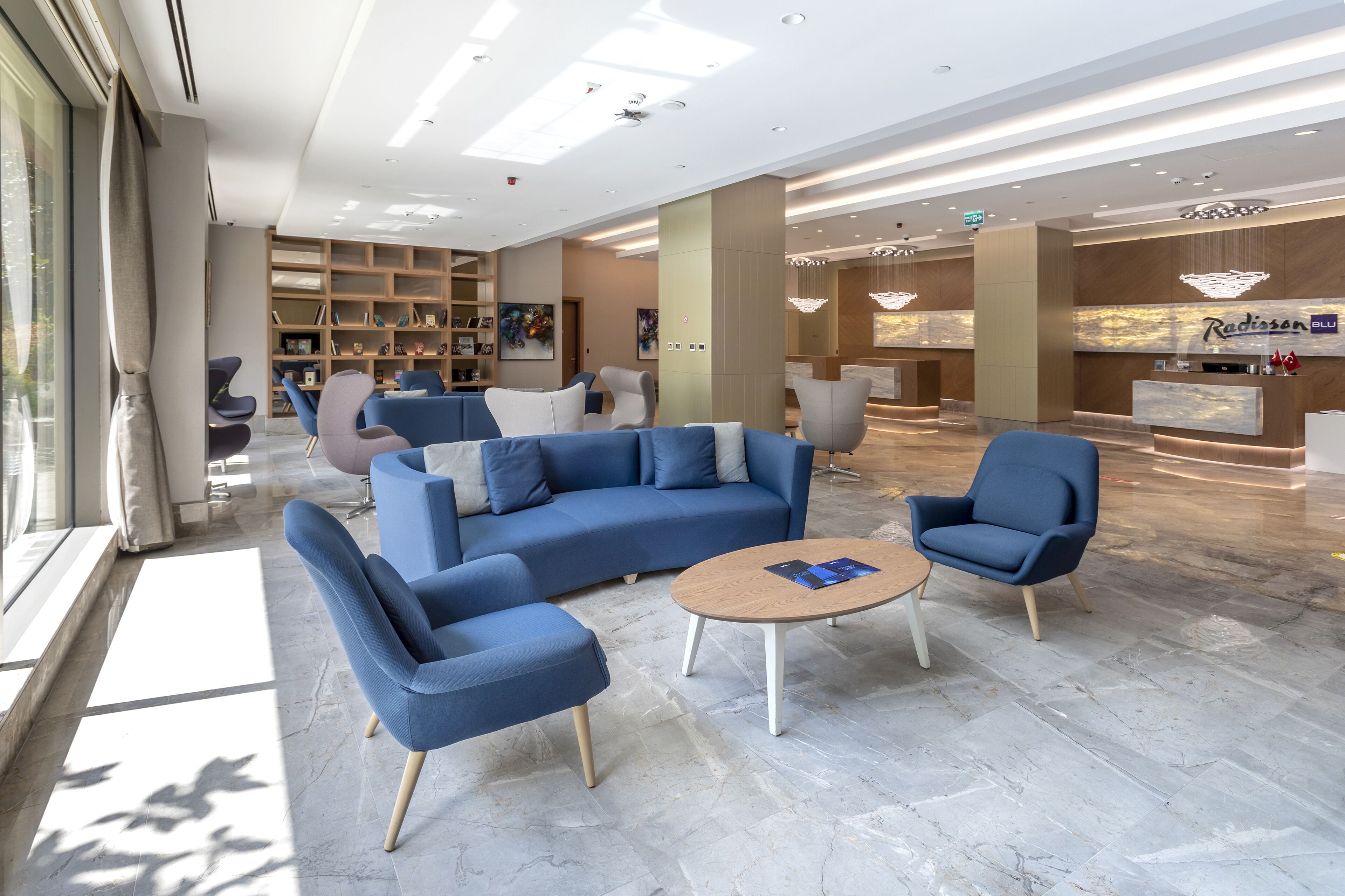 Een moderne lobby met een blauwe zithoek, een salontafel en een receptiebalie.