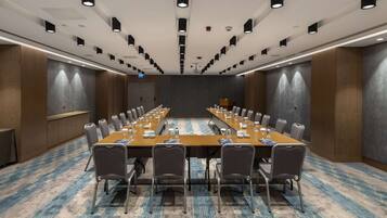 Un salón de conferencias con una mesa larga, sillas y piso alfombrado.