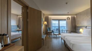 Habitación de hotel con cama, escritorio, silla, una mesita y vista al mar.