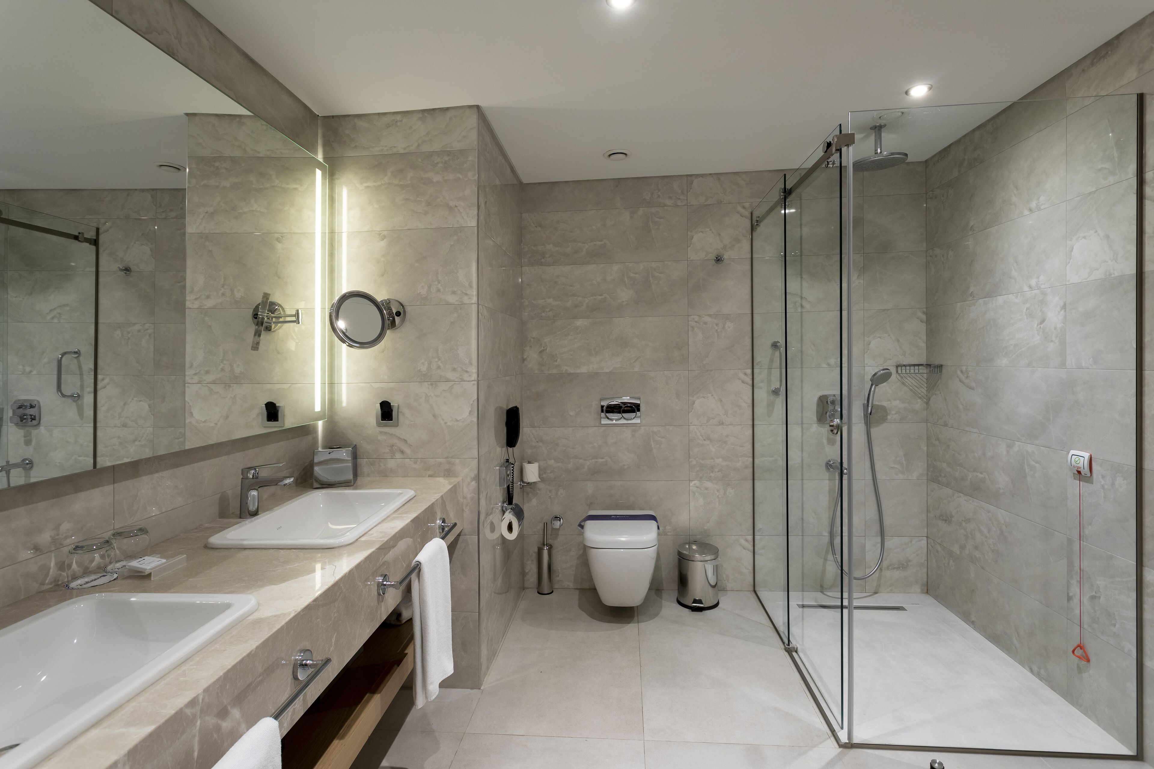 Ein modernes Badezimmer mit zwei Waschbecken, einer Toilette und einer Duschkabine.