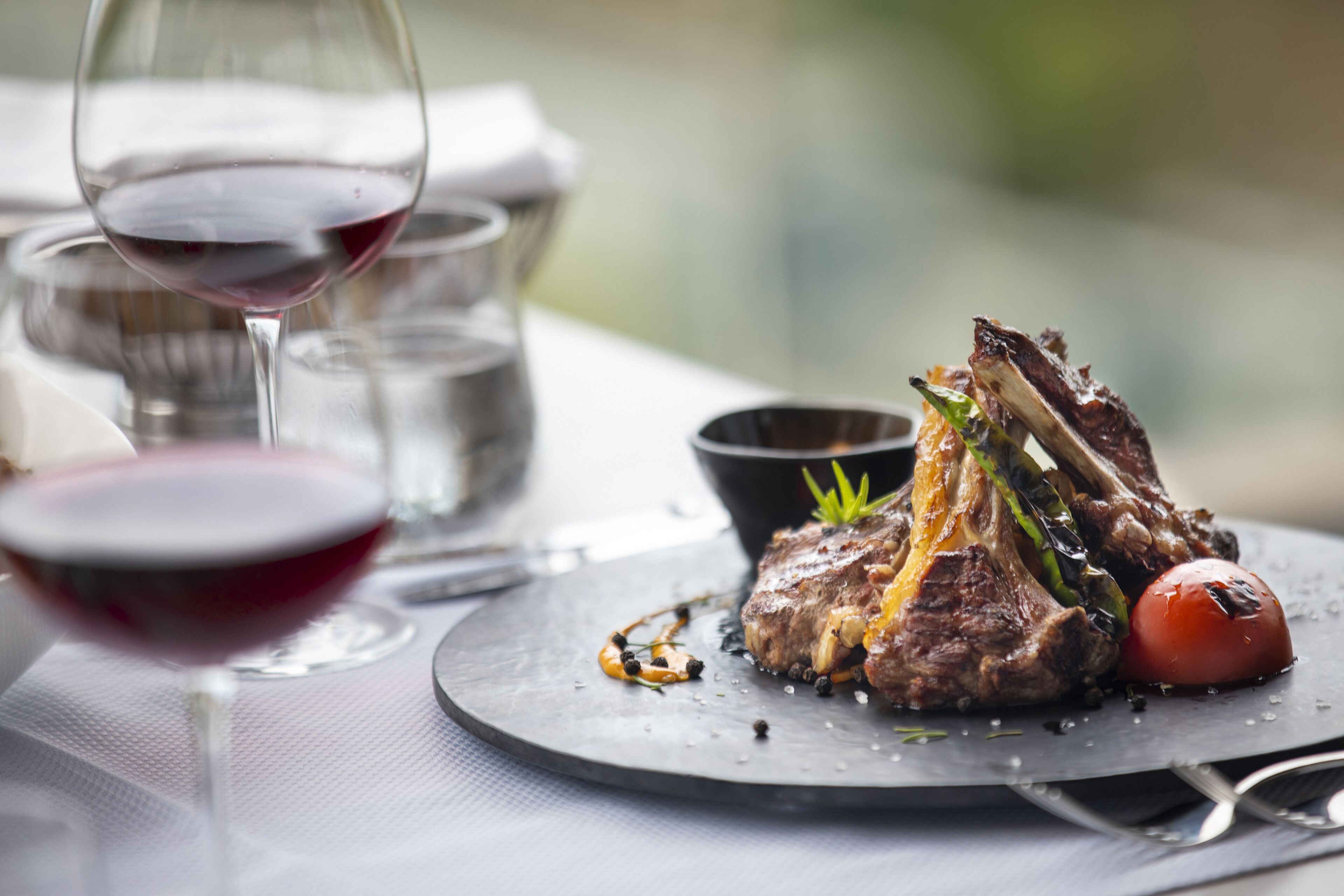 A dining table with a plate of food, a glass of red wine, and a glass of water.