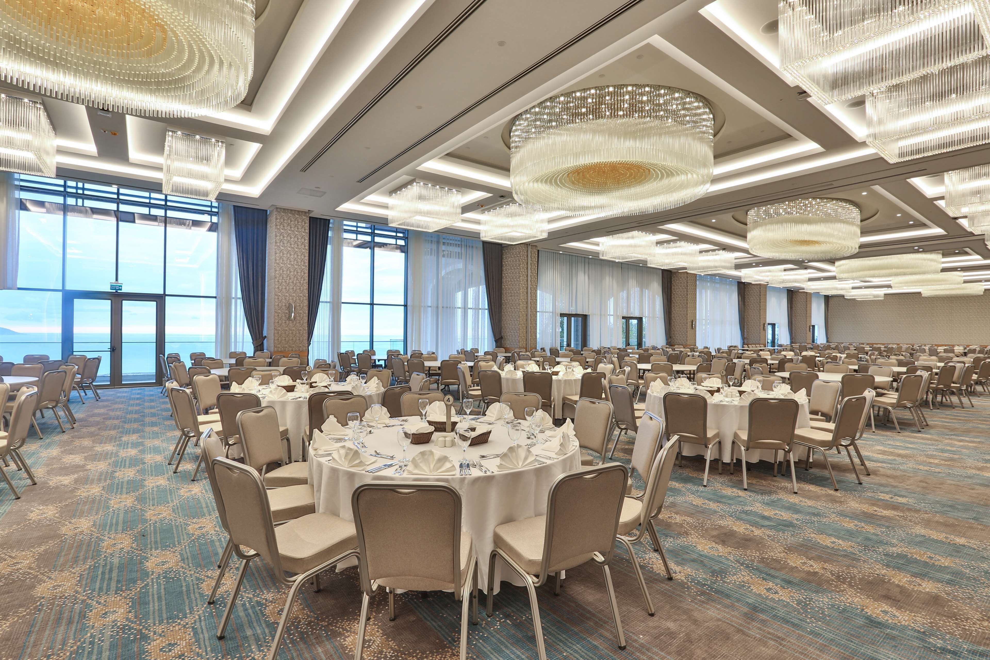 Un amplio salón de banquetes con mesas redondas, sillas y candelabros.