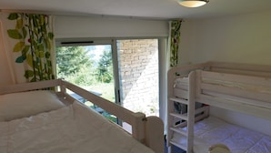 A room with bunk beds, a window with a view of greenery, and a brick wall. - Chalet in La Norma near Ski Lifts (La Norma)