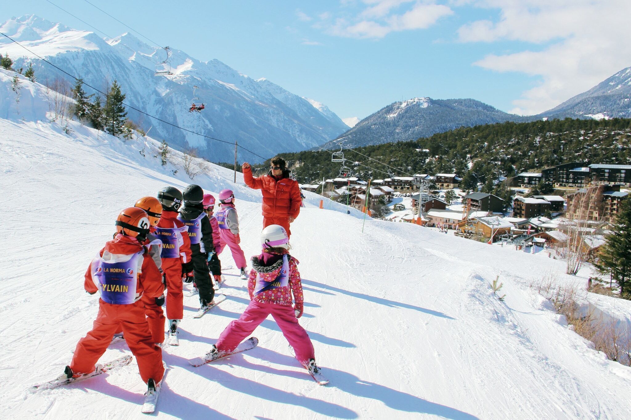 A ski slope with skiers in red and pink outfits.