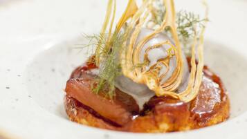 A dish with a crispy base, garnished with herbs and thin strips of onion.
