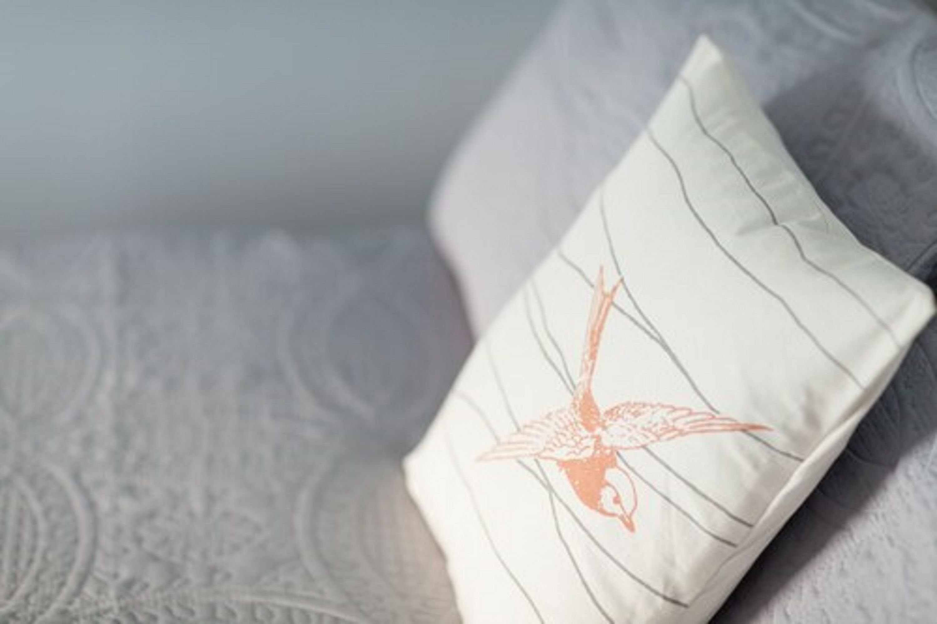 Un coussin orné d’un motif d’oiseau sur un tissu texturé.
