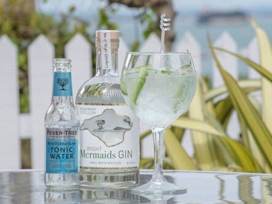 A bottle of Fever-Tree Mediterranean Tonic Water and a glass of Wight's Gin with a mint garnish on a table.