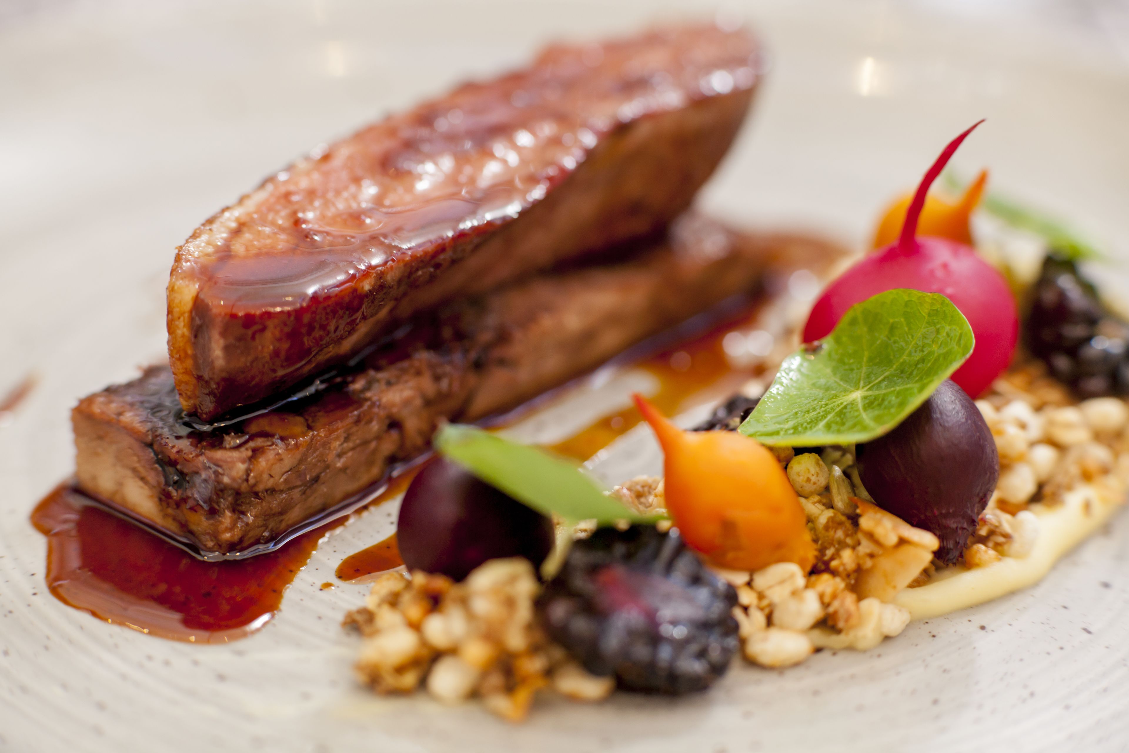 A dish with meat, vegetables, and nuts on a plate.