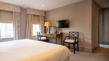 A hotel room with a large bed, a desk with a chair, a television, and curtains.
