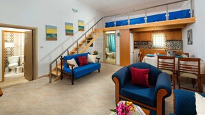A spacious living area with a blue sofa, a wooden dining table, and a staircase leading to an upper level. - Charming Beach House with private pool in South Rhodes, Beach Pearl (Gennadi)