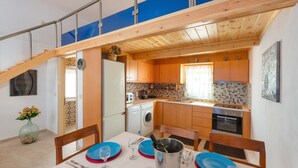 A modern kitchen with wooden cabinets, a dining area with blue plates, and a dining table set for four. - Charming Beach House with private pool in South Rhodes, Beach Pearl (Gennadi)