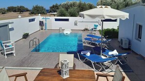 A rooftop pool area with a clear view of the sea, surrounded by white walls and blue lounge chairs. - Charming Beach House with private pool in South Rhodes, Beach Pearl (Gennadi)