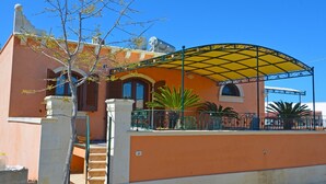 A building with a curved yellow canopy, a staircase, and a palm tree. - Luxury villa with large terrace overlooking the sea and a few steps from the sea (Marina San Gregorio)