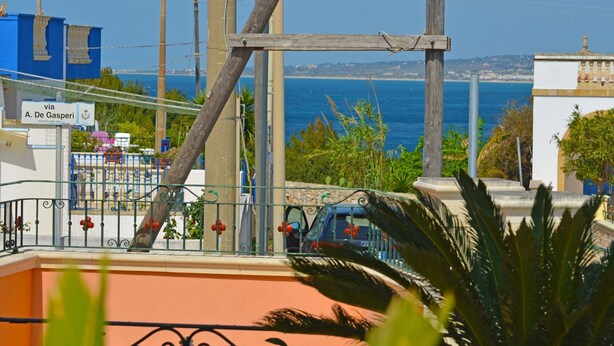 A coastal view with a wooden fence, a car, and a building with a sign reading "via A. De Gasperi". - Luxury villa with large terrace overlooking the sea and a few steps from the sea (Marina San Gregorio)
