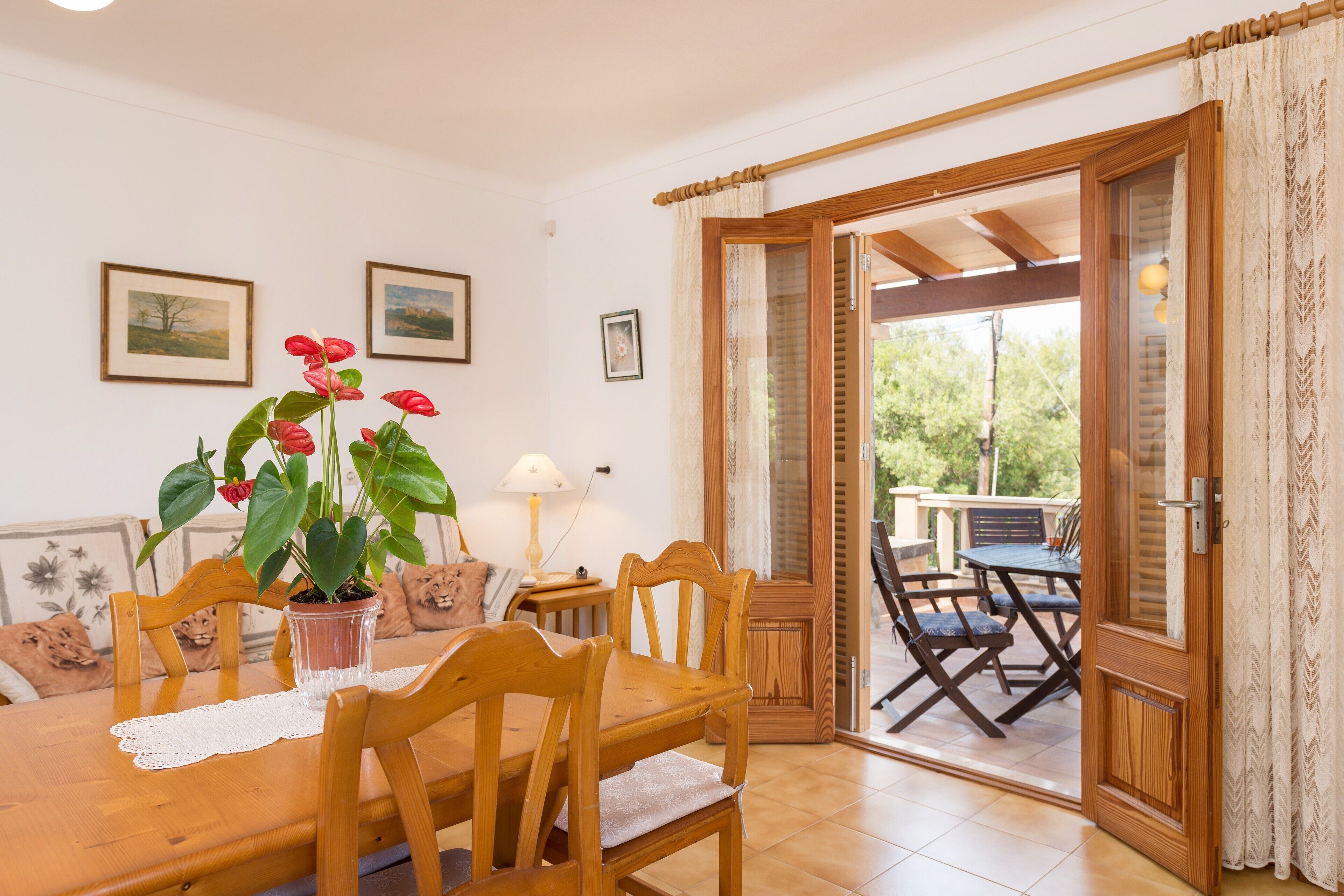 Comedor con mobiliario de madera, una planta en maceta y cuadros en la pared.
