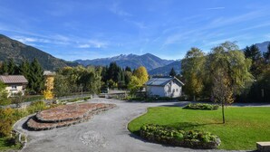 A rural setting with a paved area, a grassy field, and a building with a sloped roof.