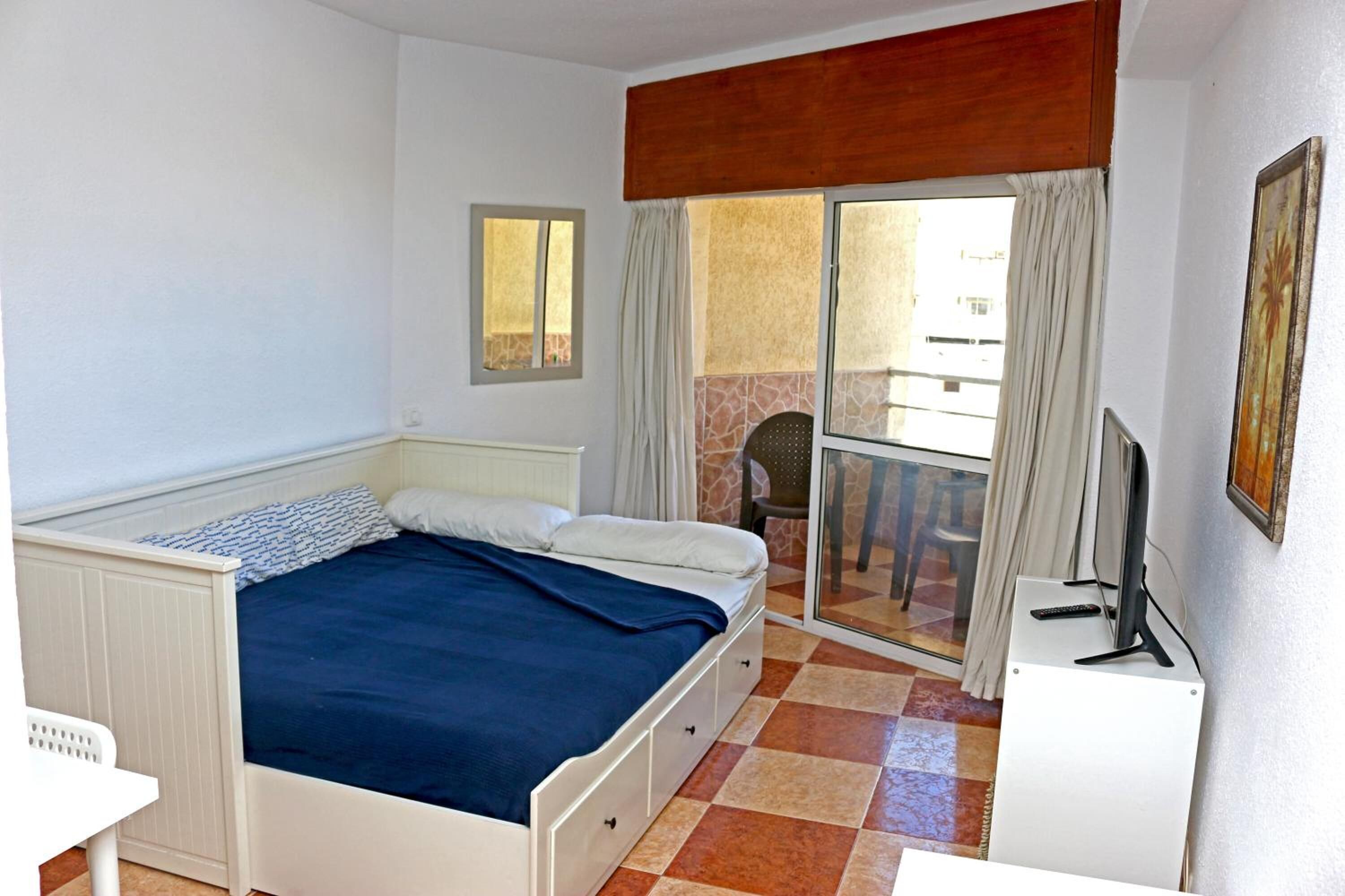 Une chambre avec un lit, un bureau, une télévision et une vue sur l’extérieur.
