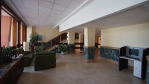 A spacious lobby with a high ceiling, a staircase, green seating area, and a desk with a computer. - Tamarindos (Benalmádena)