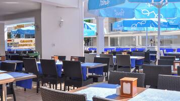 A restaurant with blue tables and chairs, and umbrellas with the word "Paraf" on them.