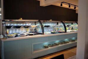 Um buffet com diversos pontos de serviço, um relógio digital e uma variedade de pratos.