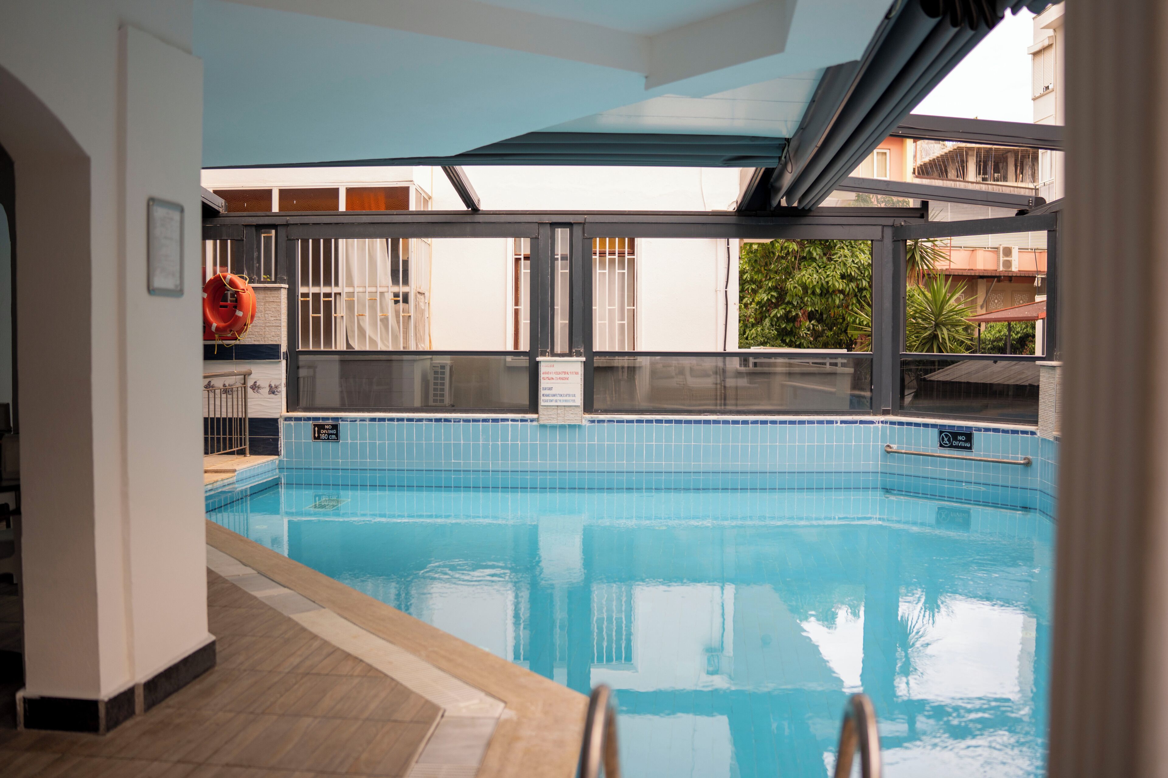 An indoor swimming pool with clear blue water, a tiled floor, and a glass barrier.