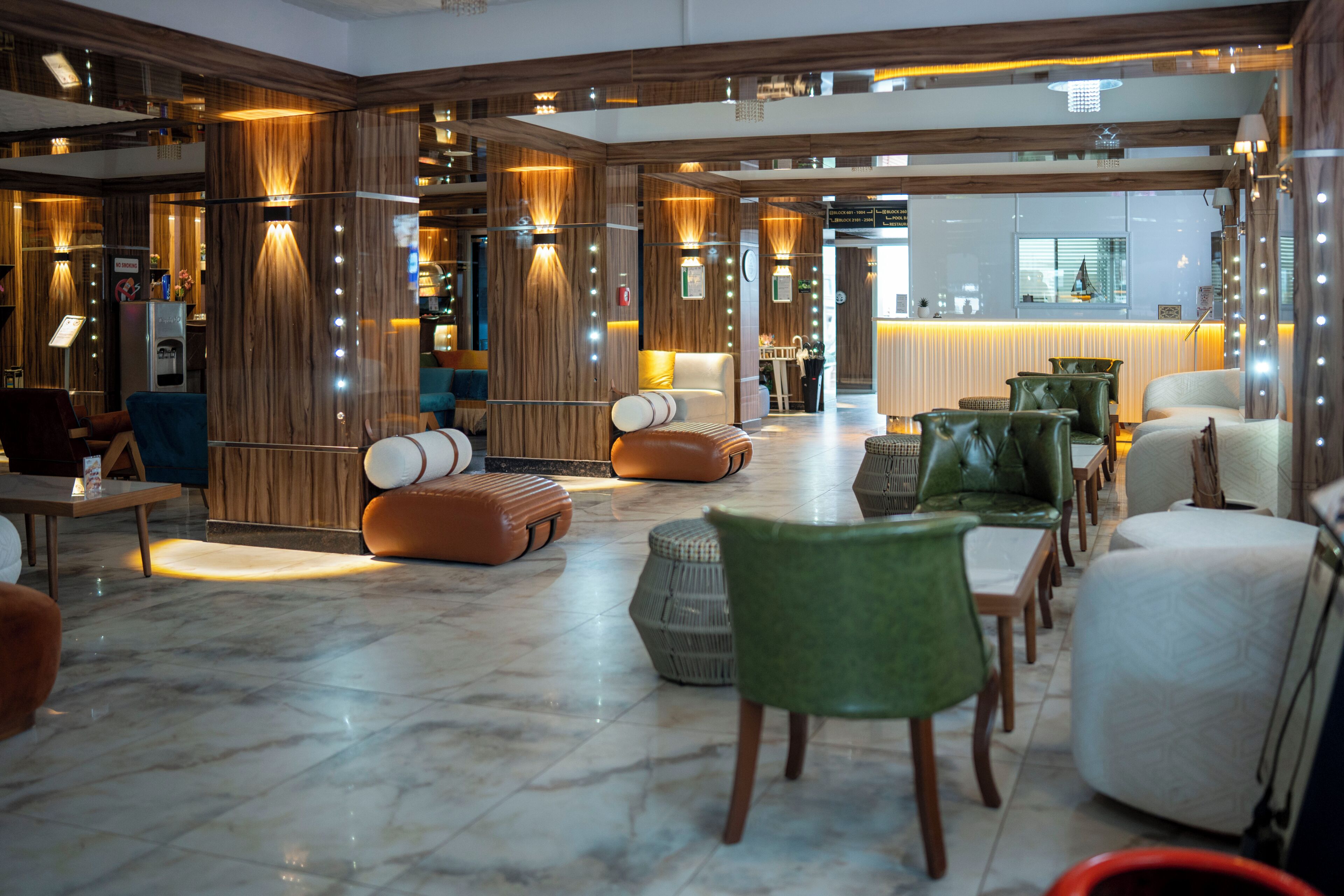 A spacious lobby with a marble floor, wooden paneling, and a reception desk.