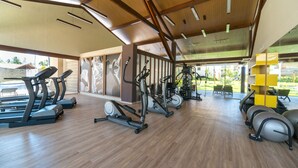 A gym with various exercise machines, wooden flooring, and large windows allowing natural light. - MLW203 Flat at beach Muro Alto 6 people (Ipojuca)