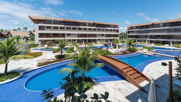 A resort with a large swimming pool, multiple balconies, and palm trees. - MLW203 Flat at beach Muro Alto 6 people (Ipojuca)