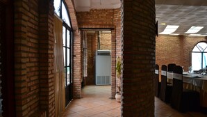 Un pasillo amplio con paredes de ladrillo, ventanas grandes y una unidad central de aire acondicionado.