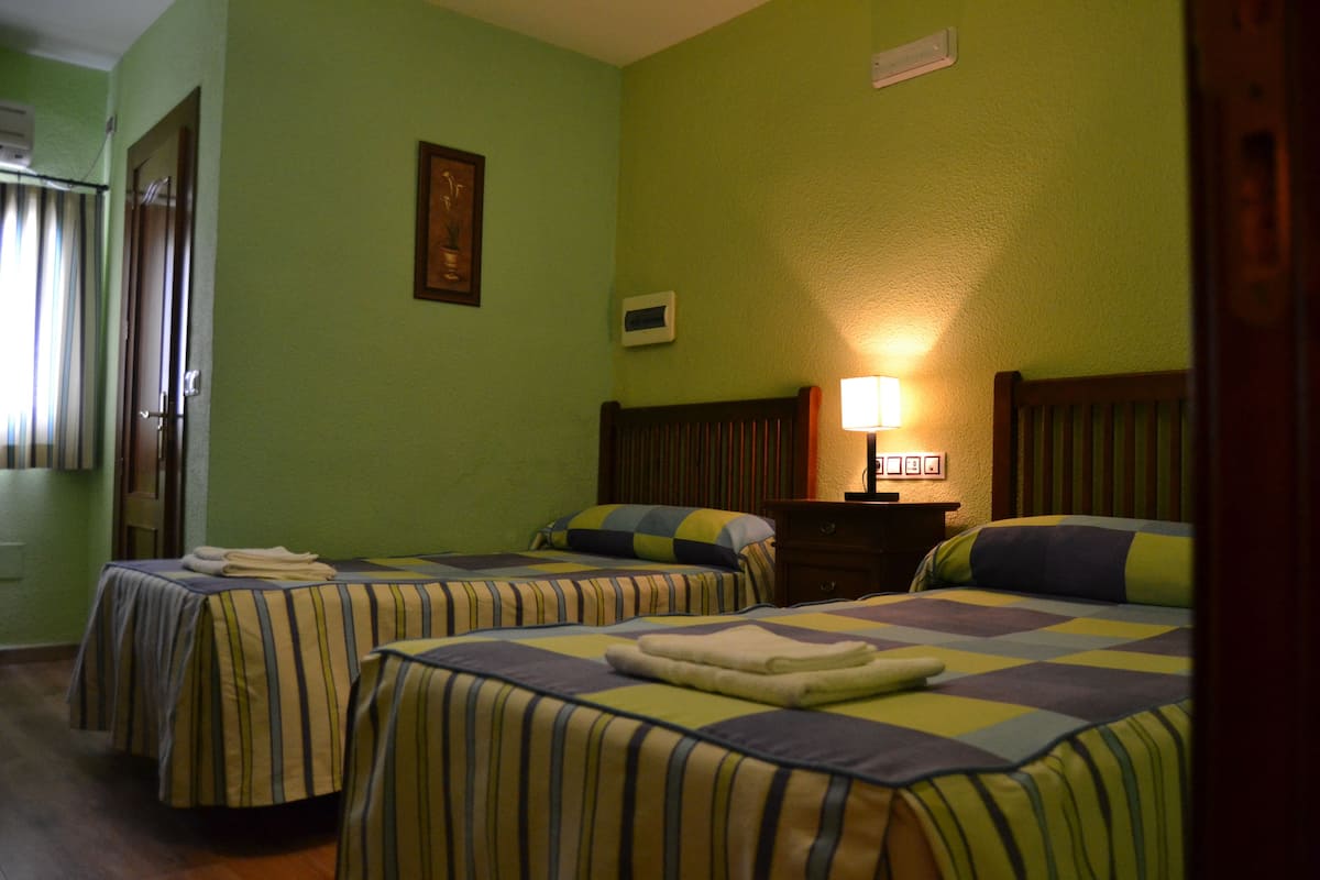 A hotel room with two beds, a nightstand, and a lamp.
