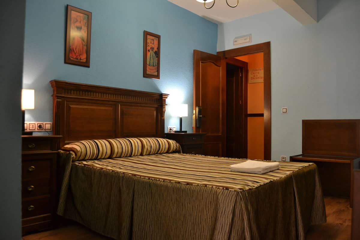 A neatly made bed with a striped bedspread, a wooden headboard, and a bedside table with a lamp.