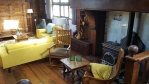 A cozy living room with a yellow sofa, wooden chairs, a fireplace, and a radiator. - De Zwerver (Naarden)