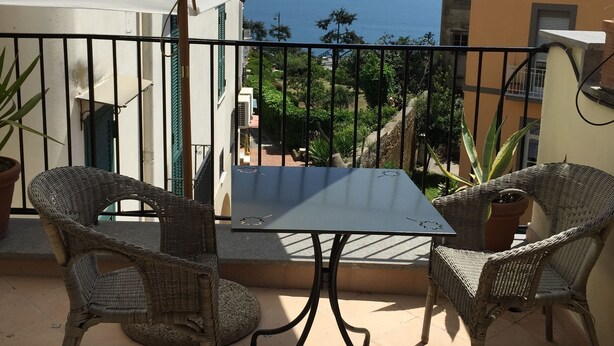 A balcony with a table and chairs, a white umbrella, and a view of the sea. - House in historic villa absolute tranquility sea and center Naples (Napoli)