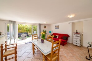 A dining area with a table and chairs, a red sofa, and a balcony with outdoor furniture. - Homerez - House in Arles sur Tech (Arles sur Tech)