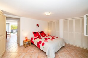 A bedroom with a bed, a nightstand, a lamp, and a view of the outside. - Homerez - House in Arles sur Tech (Arles sur Tech)
