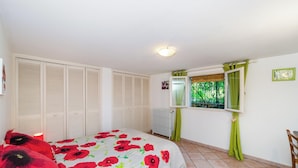 A bedroom with a bed, a window with curtains, a radiator, and a wardrobe.