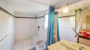 A bathroom with a shower, toilet, sink, and a mirror.