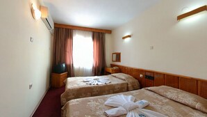 Quarto de hotel com duas camas, televisão, espelho e janela com cortinas.
