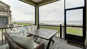Un espacio al aire libre cubierto con una mesa y mobiliario de mimbre, con vista a la playa.