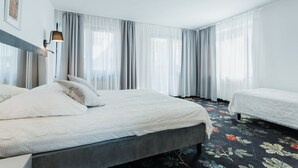 Une chambre d’hôtel moderne avec un grand lit, un lit plus petit et une table de chevet.