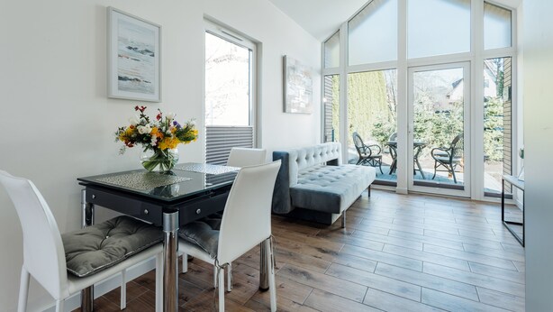 Un salon moderne avec un coin repas, de grandes fenêtres et une vue sur l’extérieur.