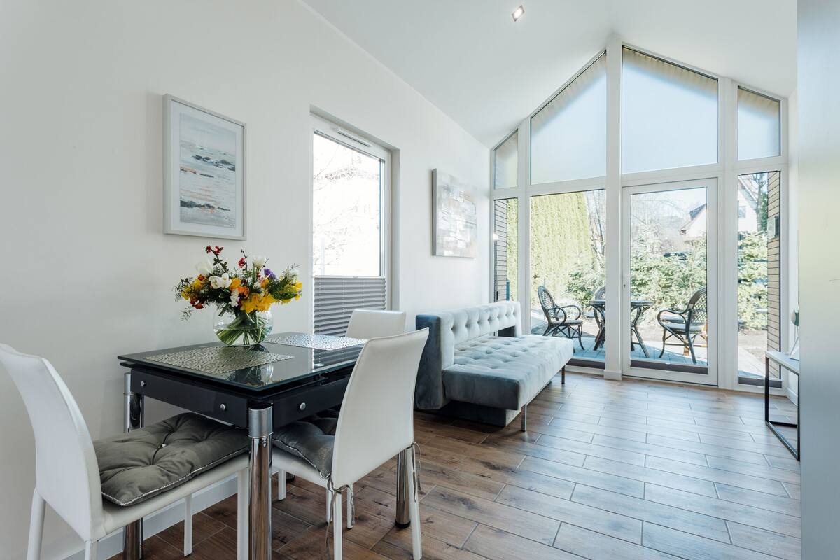 Una sala de estar moderna con comedor, ventanas amplias y vistas al exterior.