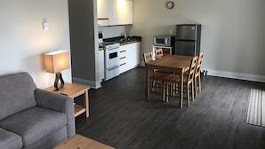 A compact living space with a kitchenette, a dining area, and a gray sofa. - The Shores of Deer Lake (Unorganized Centre Parry Sound)