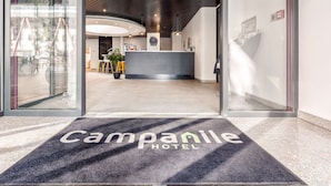 A hotel reception area with a modern design, a reception desk, and a glass entrance. - Campanile Martigny (Martigny)